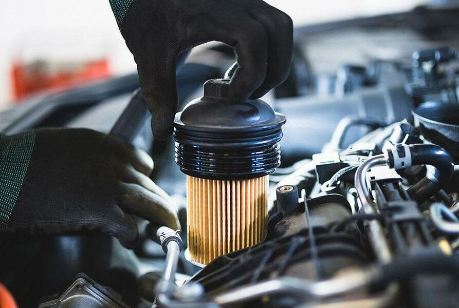 Close up hands of unrecognizable mechanic doing car service and maintenance. Oil and fuel filter changing.
